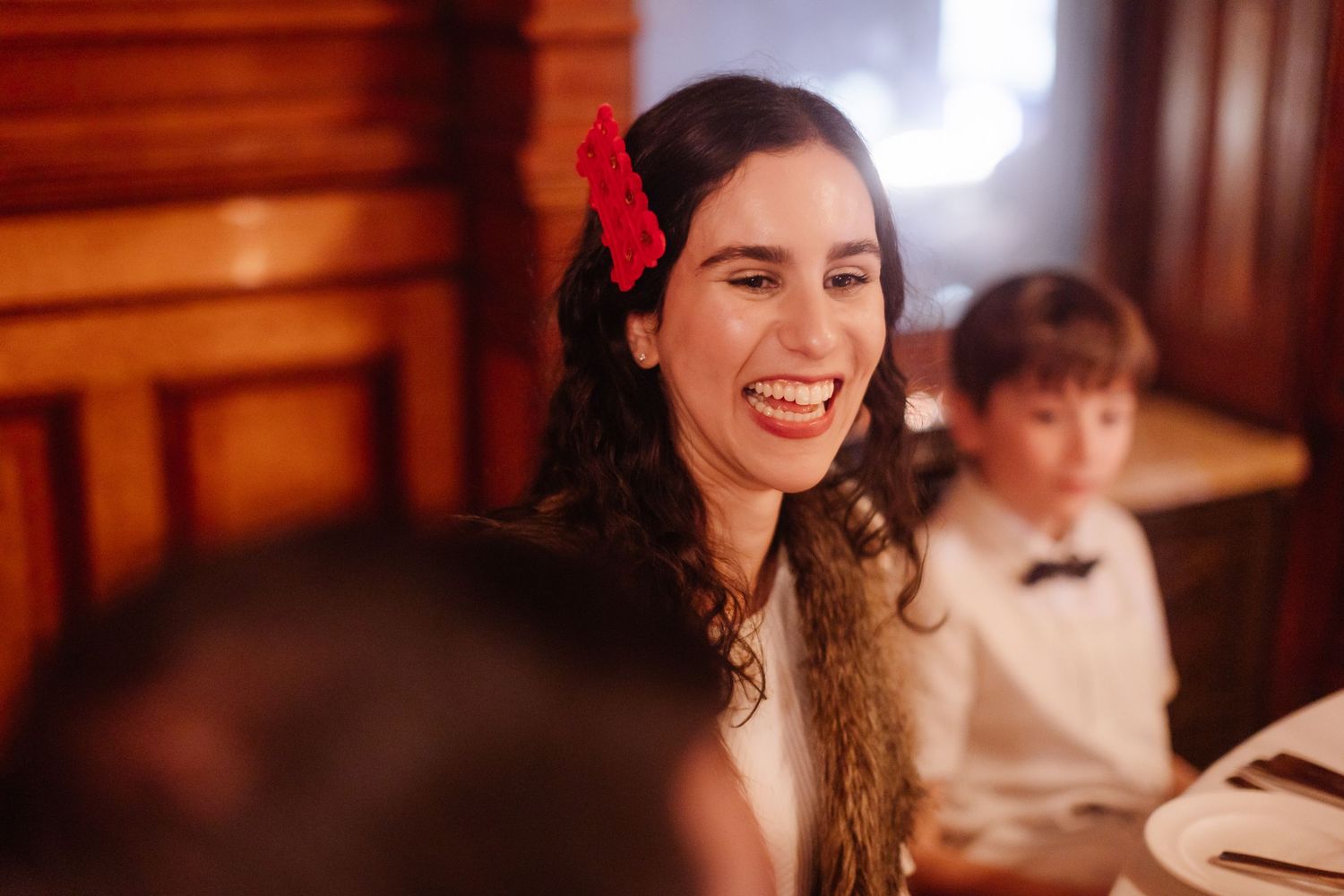 Guest in red hair accessory enjoying celebration at formal dinner event.