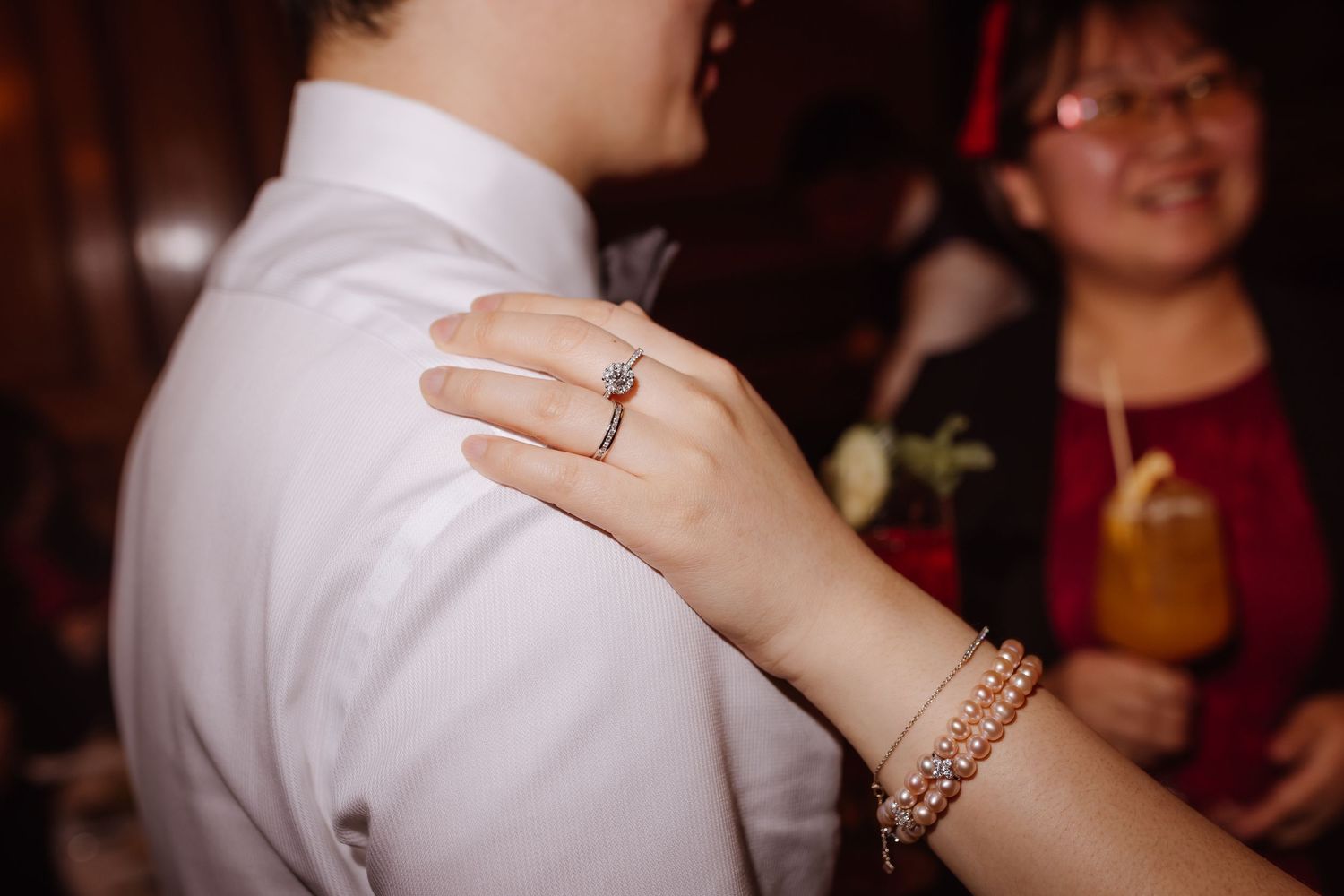 Close-up of jewelry and hands during celebratory moment at formal event.