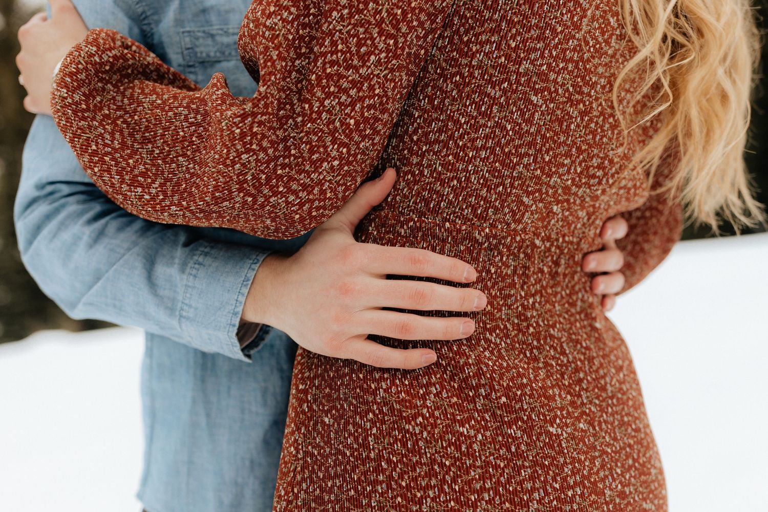 Close up of man's hands on his fiancé's waist as they hold each other