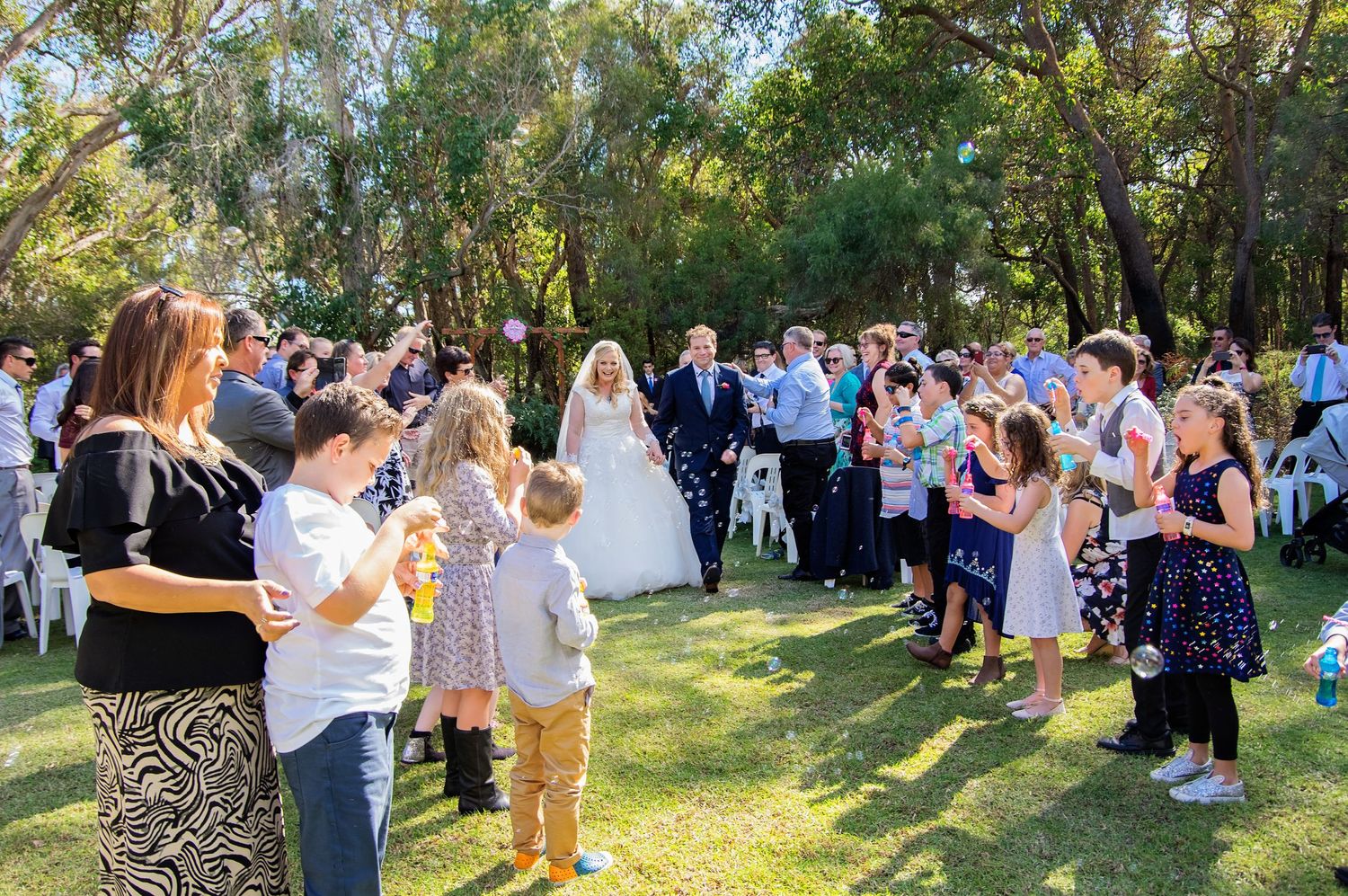 bride and groom walking down the aisle surrounded by guests and bubbles
