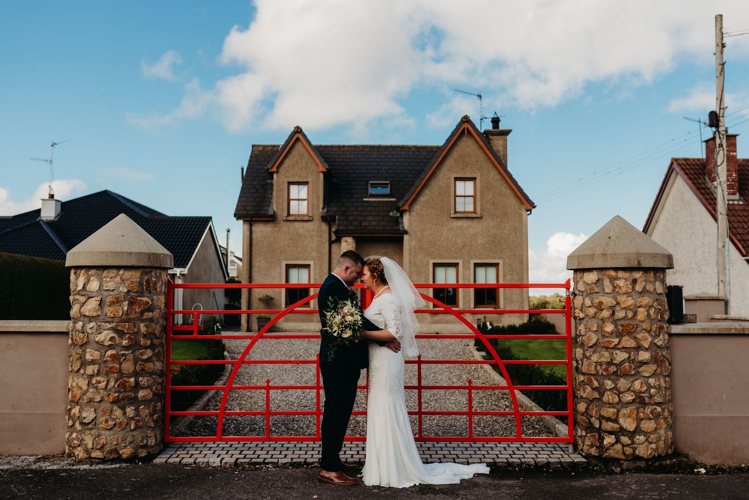 Bride and Groom, posing in front of bright red gates.