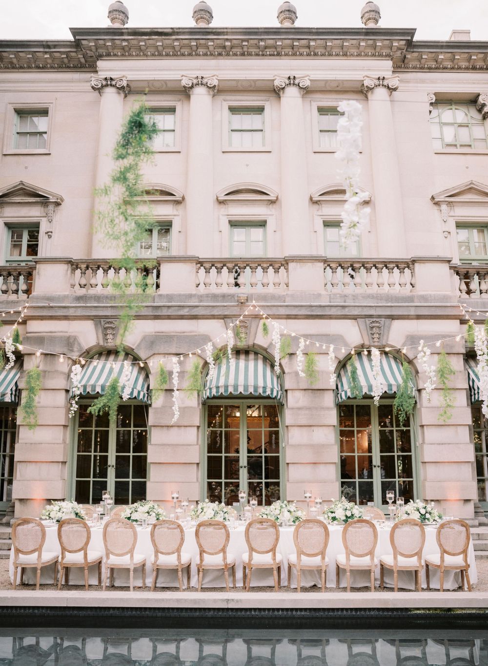 Pink historic building facade with striped awnings and elegant outdoor wedding reception setup.