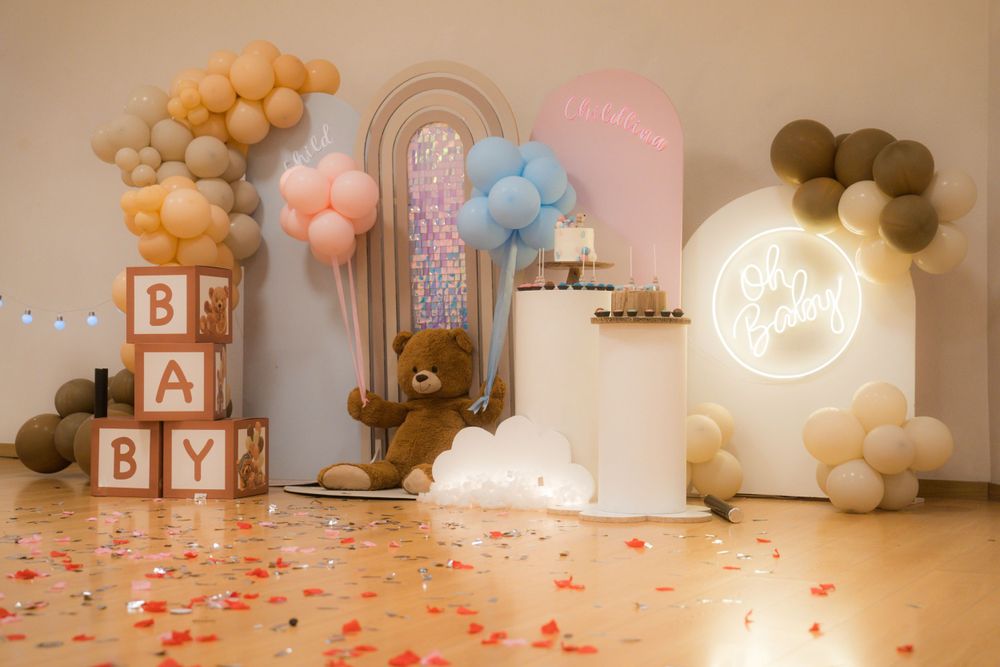 Baby shower venue decorated with balloon arches, letter blocks, and rose petals on the floor.