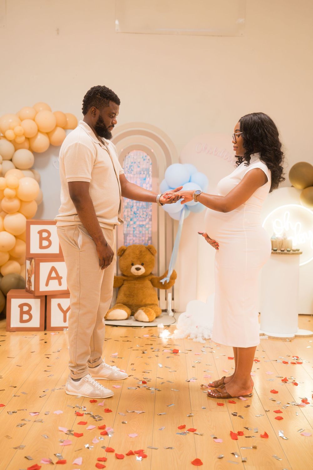 Couple celebrating at a gender reveal party with balloon decorations and letter blocks.