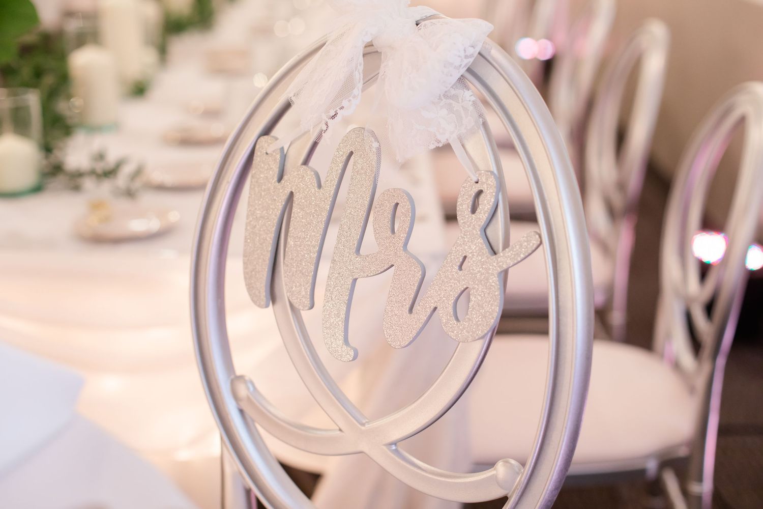 Decorative silver monogram chair signs displayed at a formal wedding reception.