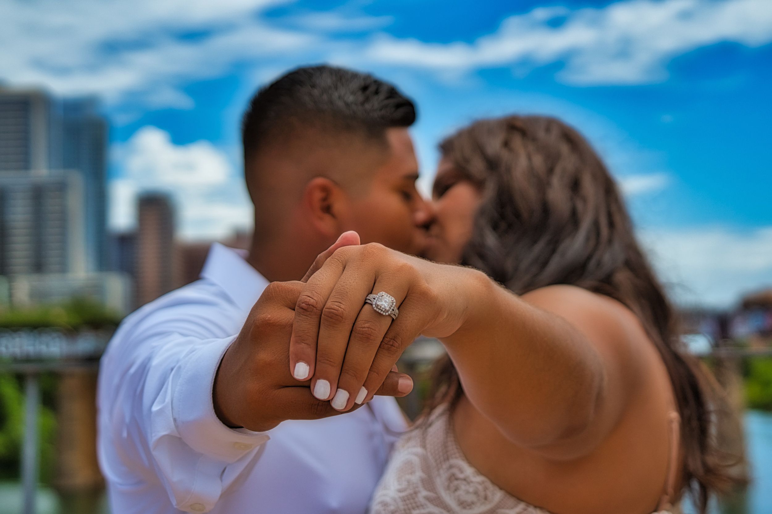 couple kissing showing off engagement ring
