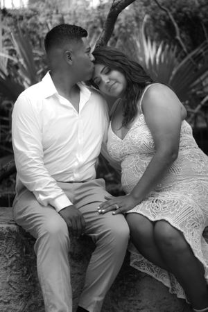 man holds woman and kisses her forehead in black and white
