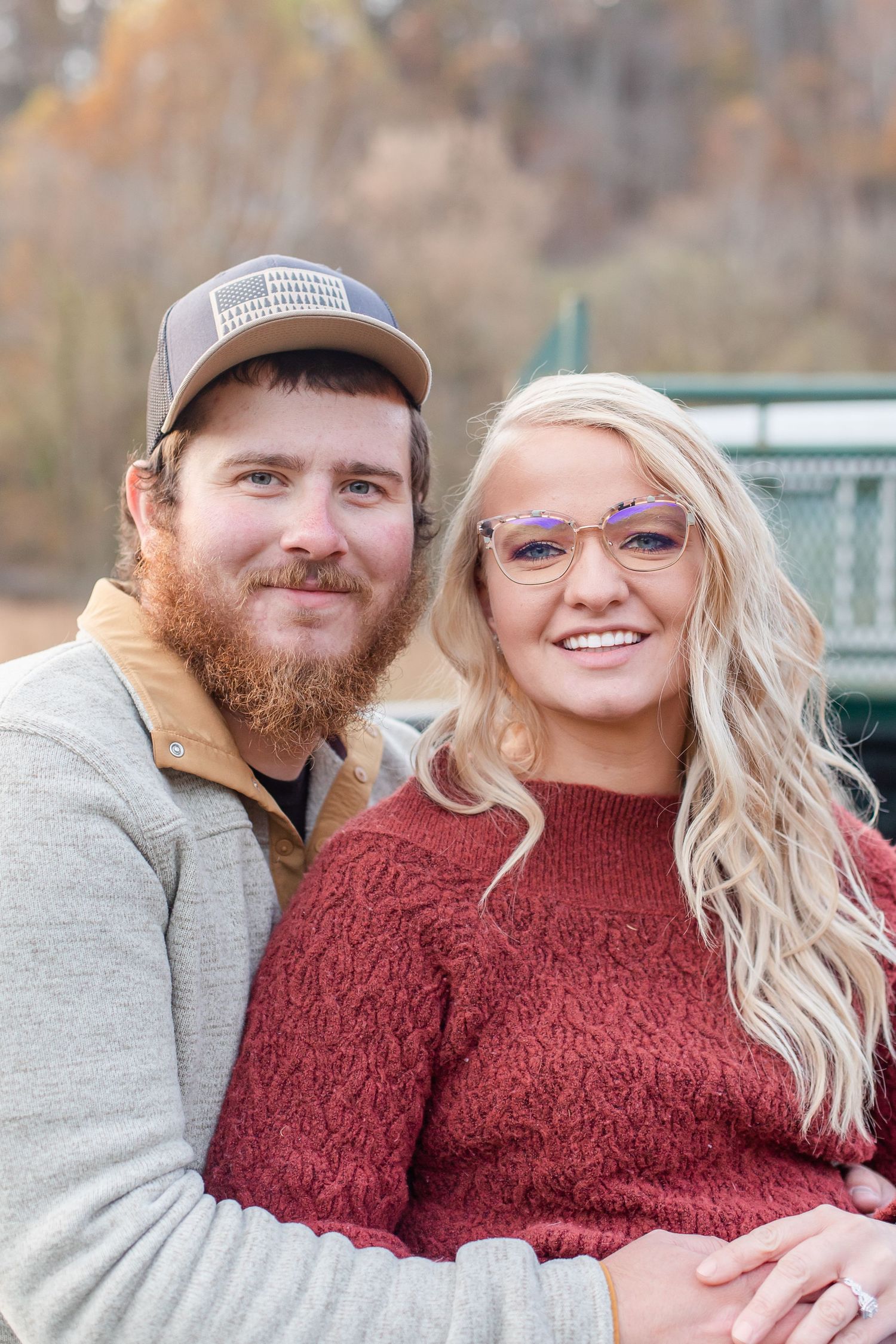 Couple in casual fall attire embracing outdoors during an autumn photo session.