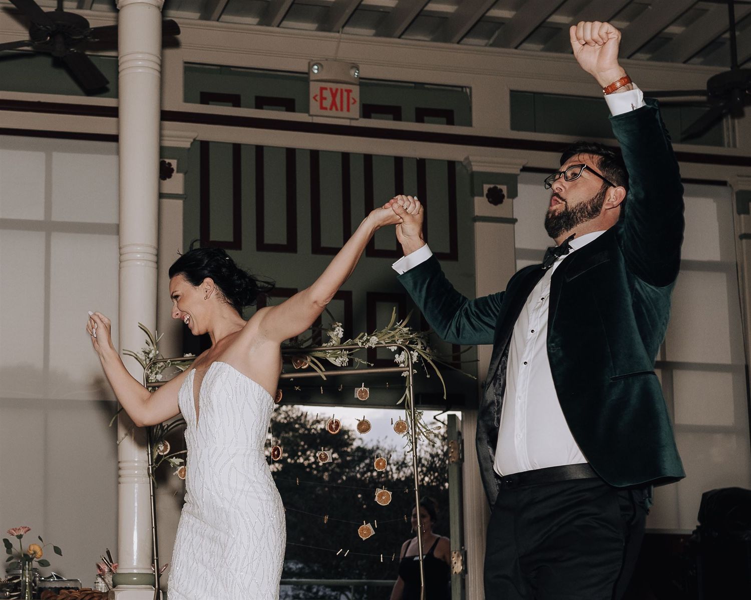 Couple celebrating on dance floor at wedding reception with arms raised in joy.