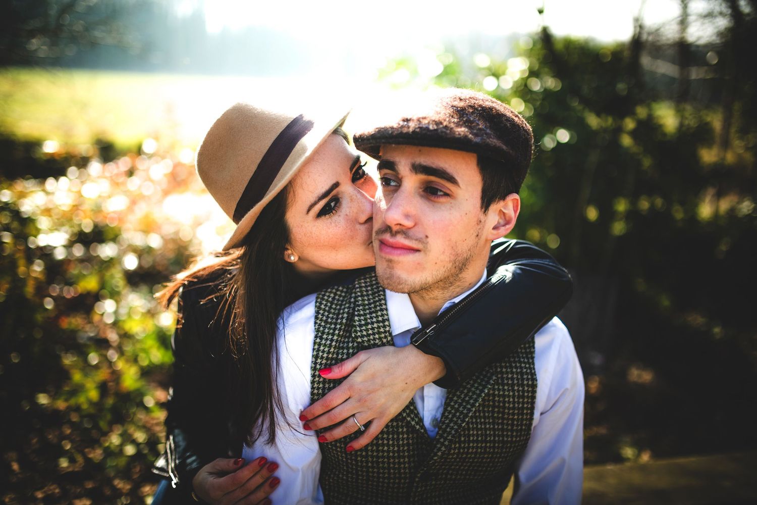 A romantic outdoor portrait of a couple embracing in golden sunlight.