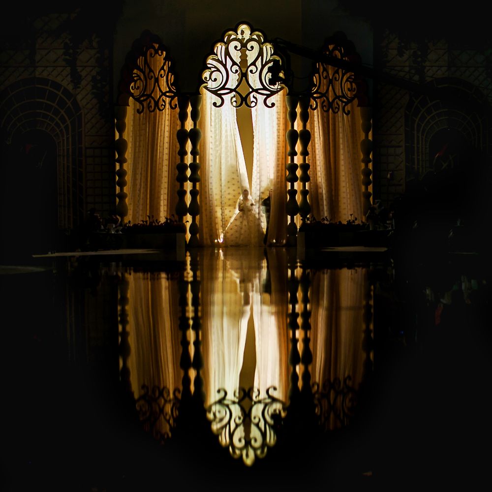 Ornate golden doorway with intricate design creates symmetrical reflection in dark setting.
