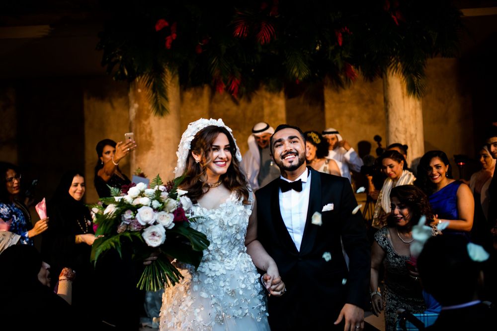 Joyful wedding celebration with guests in formal attire inside dimly lit venue.