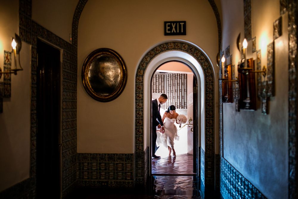 Silhouette through arched doorway capturing intimate wedding moment in historic building.