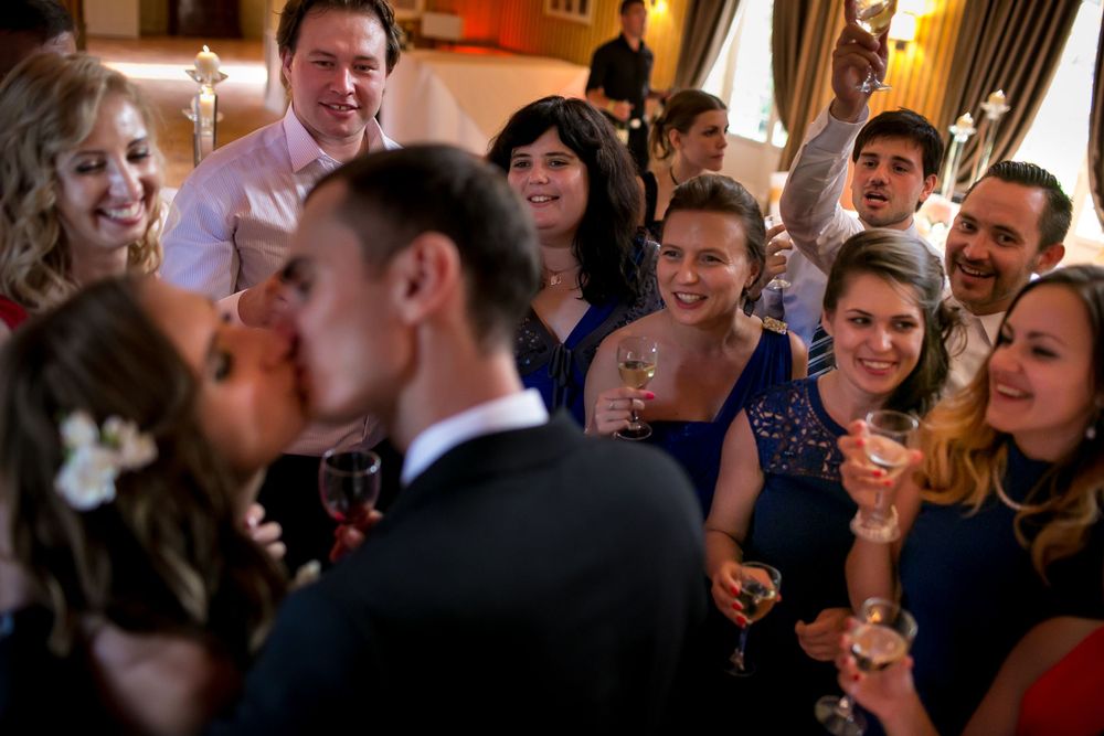 Wedding guests celebrating and watching couple share romantic moment at reception.