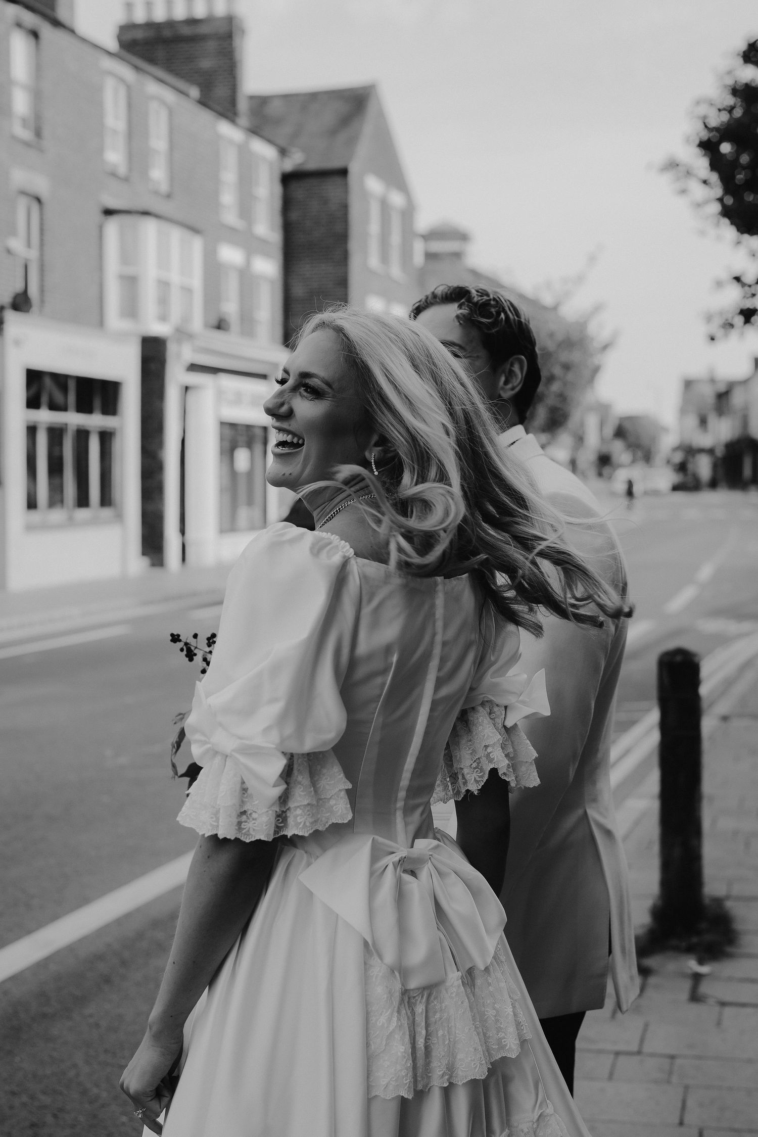 bride laughing with groom as they walk through oxford