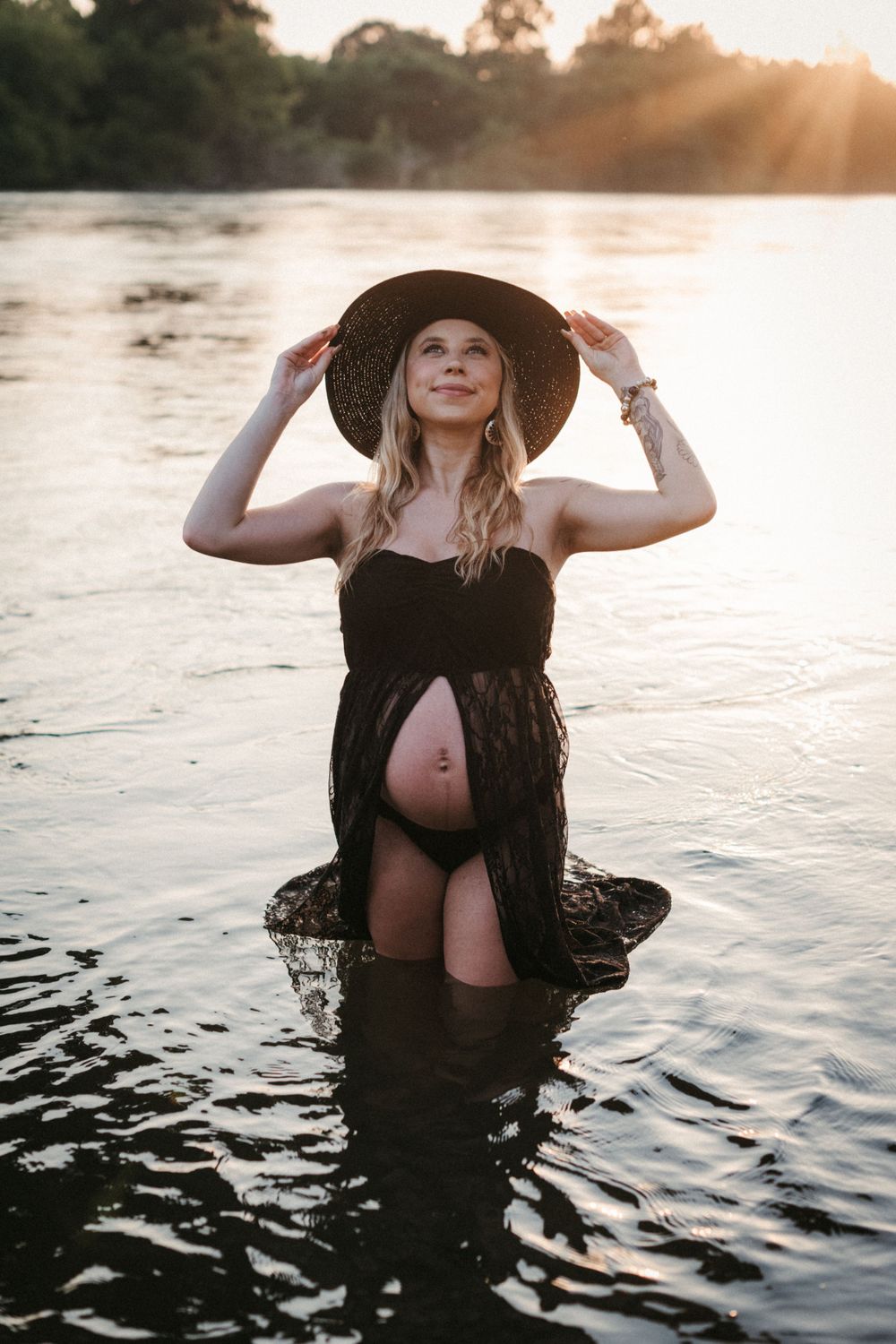 Maternity photoshoot at sunset with figure in black lace dress standing in water at Seven Islands State Birding Park.
