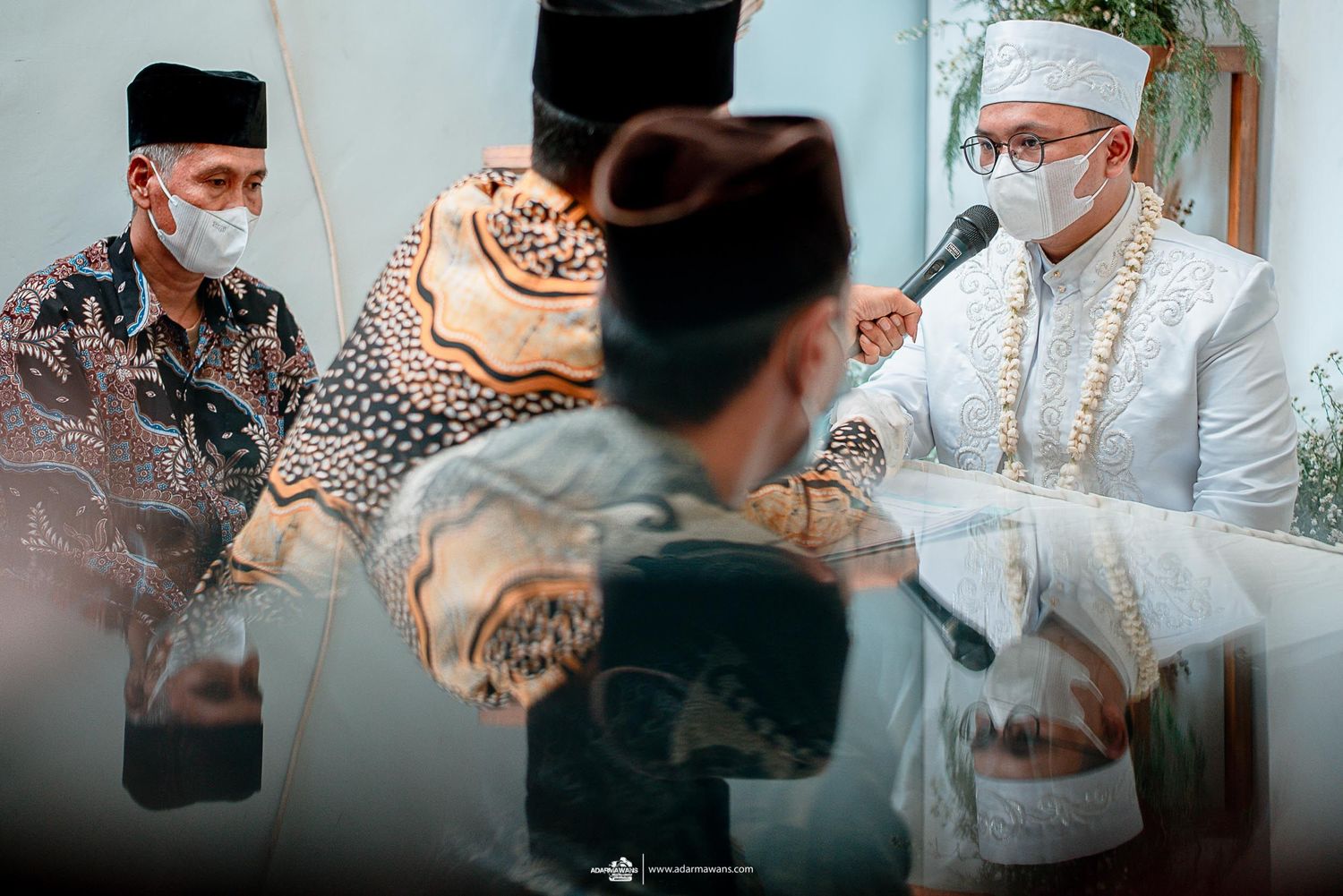 Traditional wedding ceremony with participants seated around table during document signing.