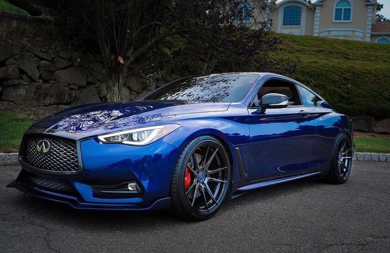 Sleek blue Infiniti Q60 sports coupe with custom wheels parked near a house.