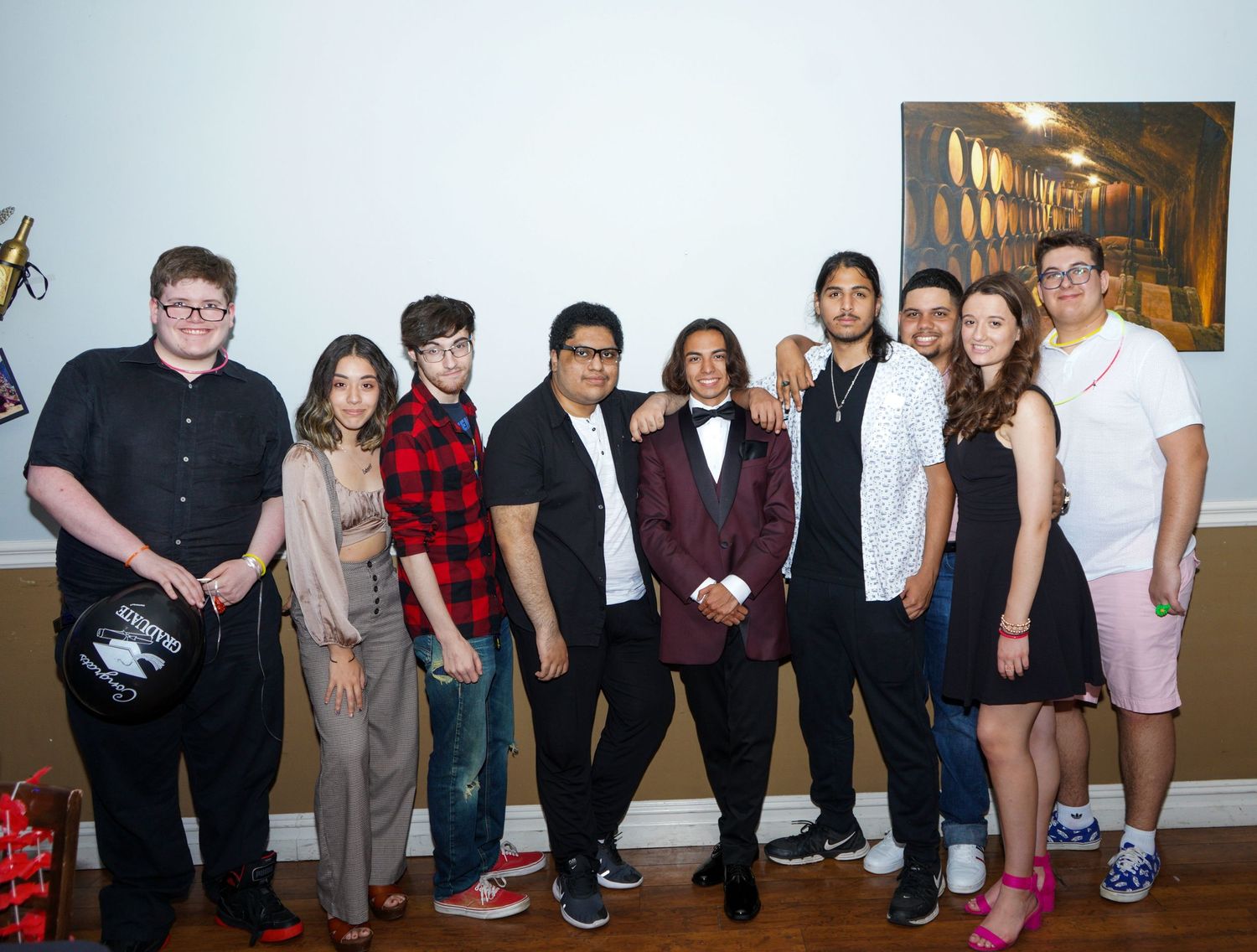 Large group photo of people posing together in casual and formal attire indoors.
