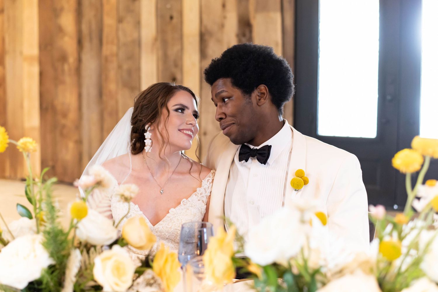 Reception celebration with yellow floral centerpieces in a rustic wooden venue.