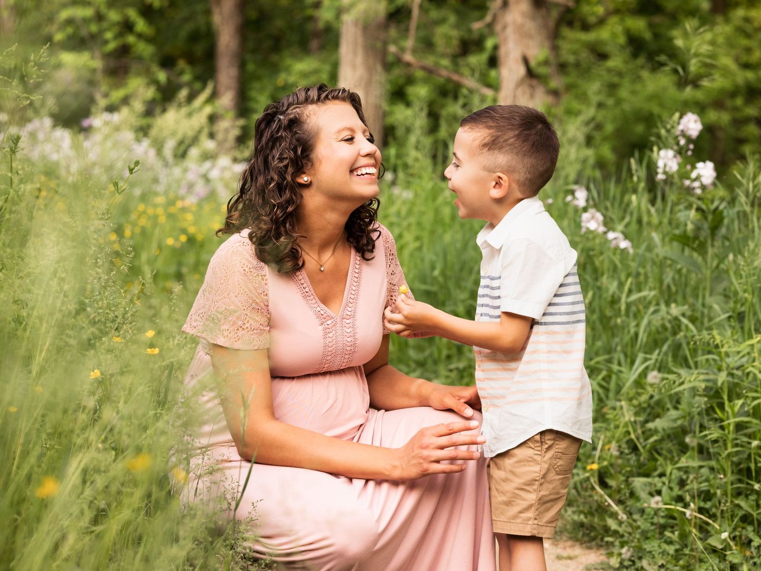 Maternity family photo session of mother and son laughing on wooded path