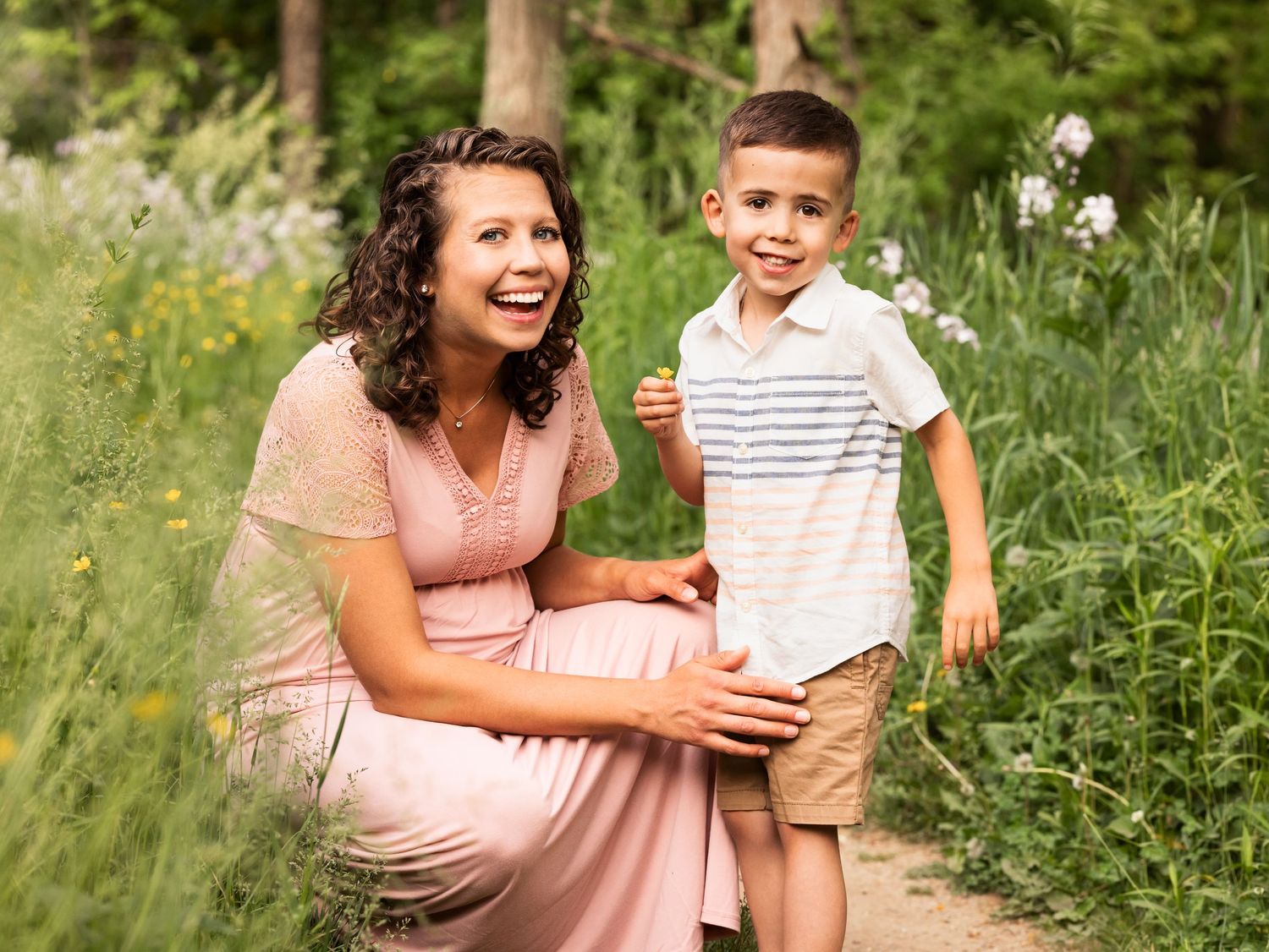 maternity family photo of mother and son laughing in woods and flowers