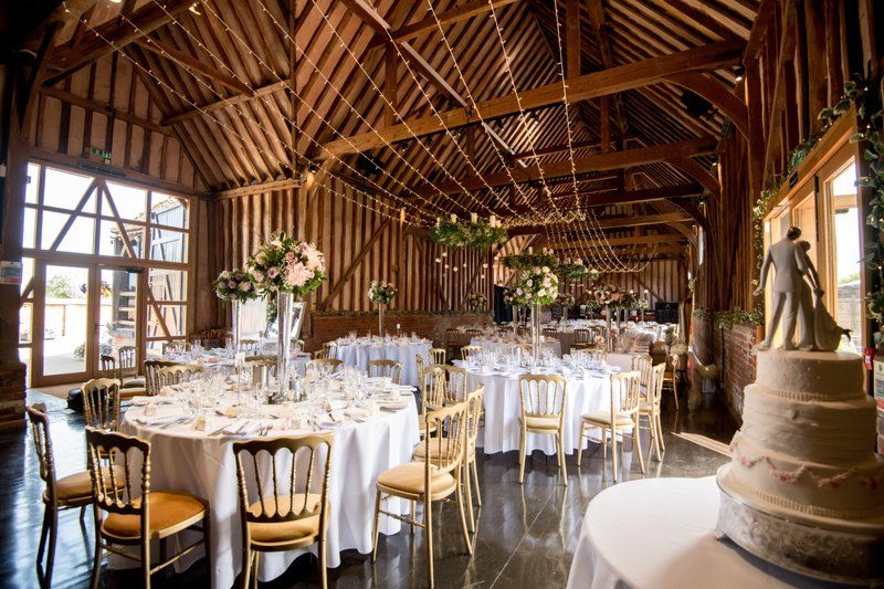 Elegant barn wedding reception venue with white tables and exposed wooden beams.