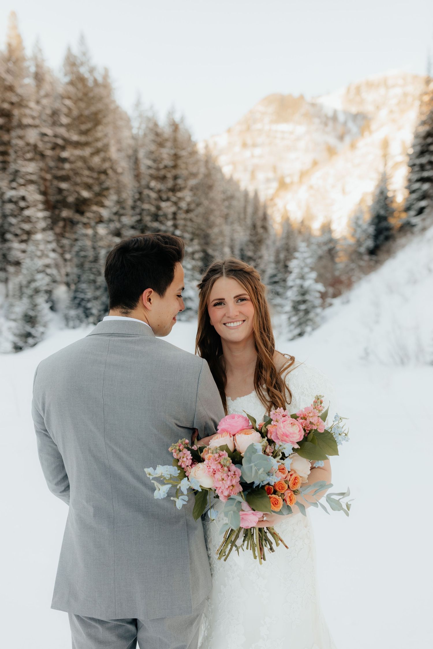 Groom looks at Bride in snowy mountains