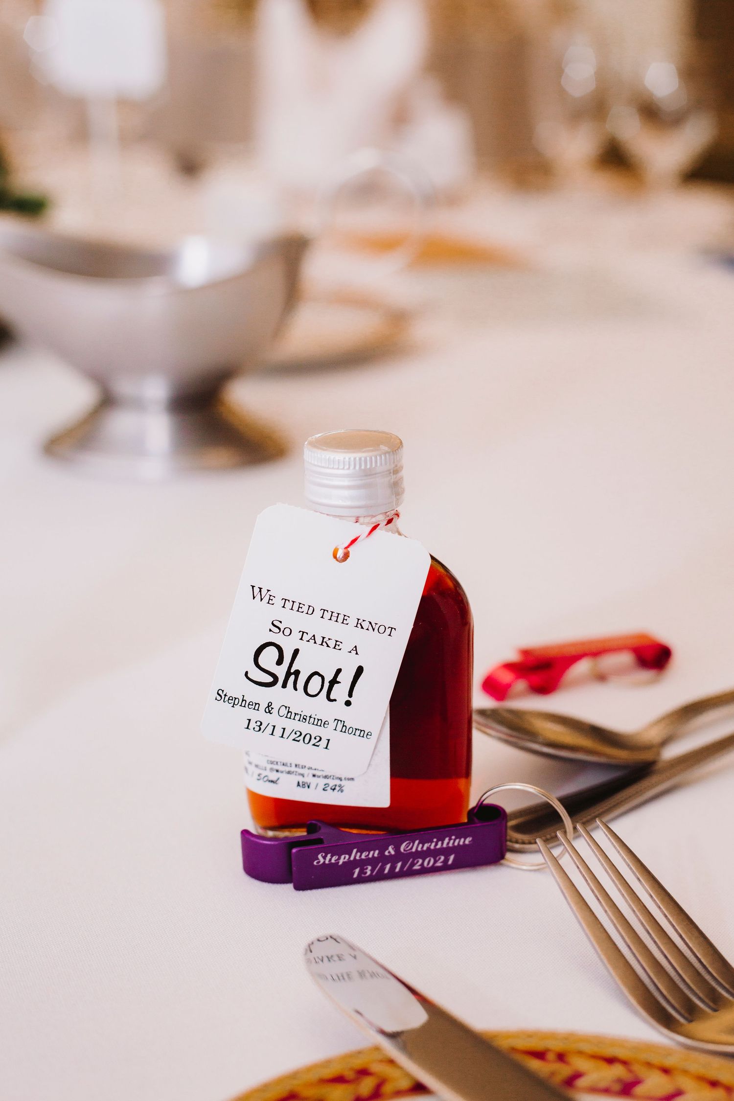 Wedding favor jars with personalized labels arranged on white tablecloth.