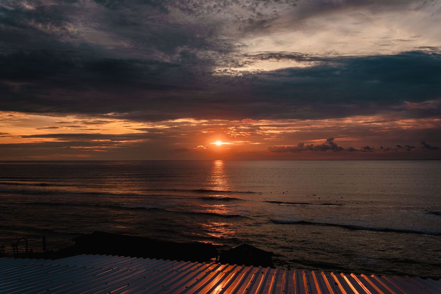 Vibrant orange sunset over ocean horizon with dramatic cloudy sky.