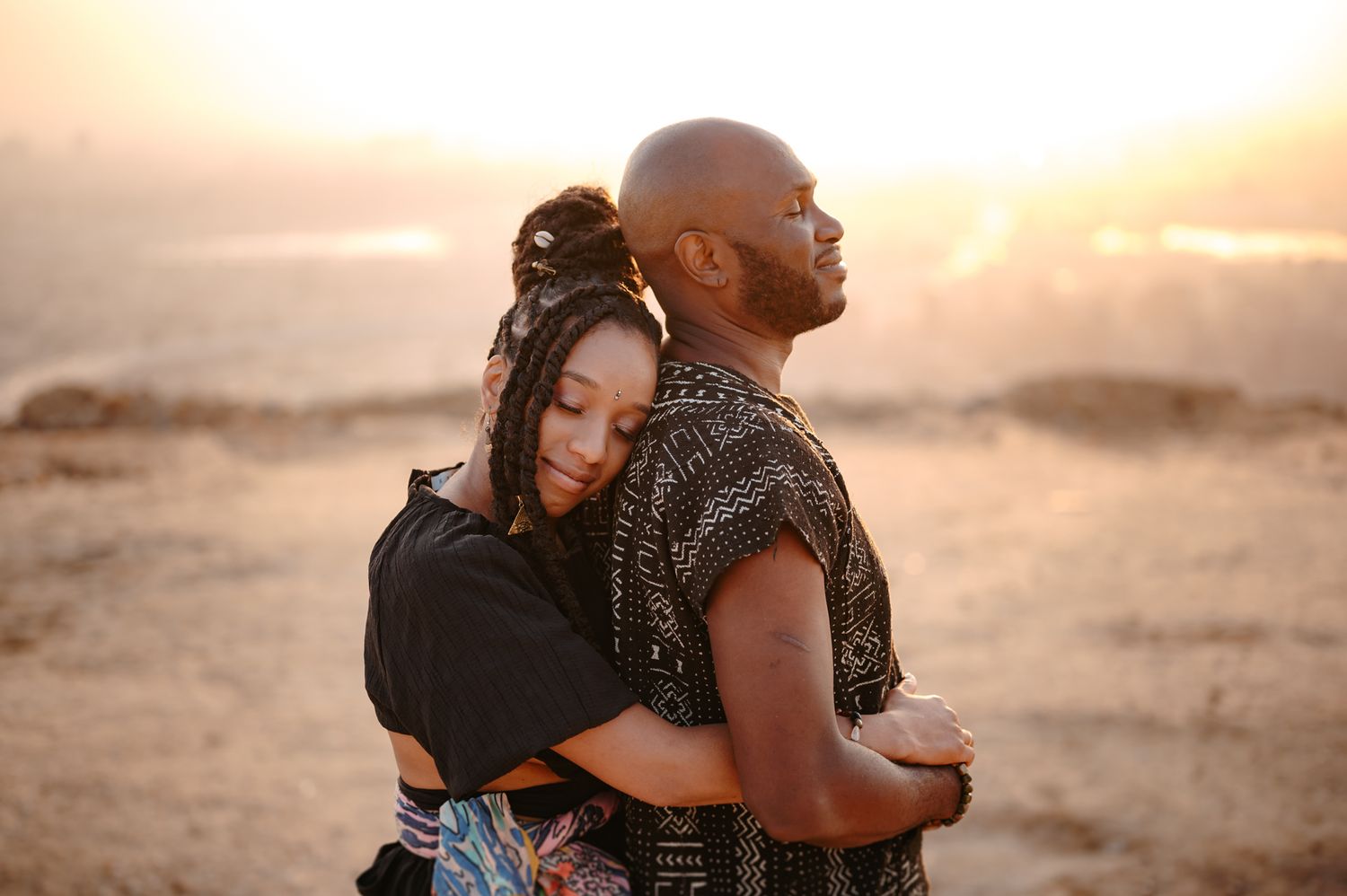 Couple embracing during sunset in a desert landscape.