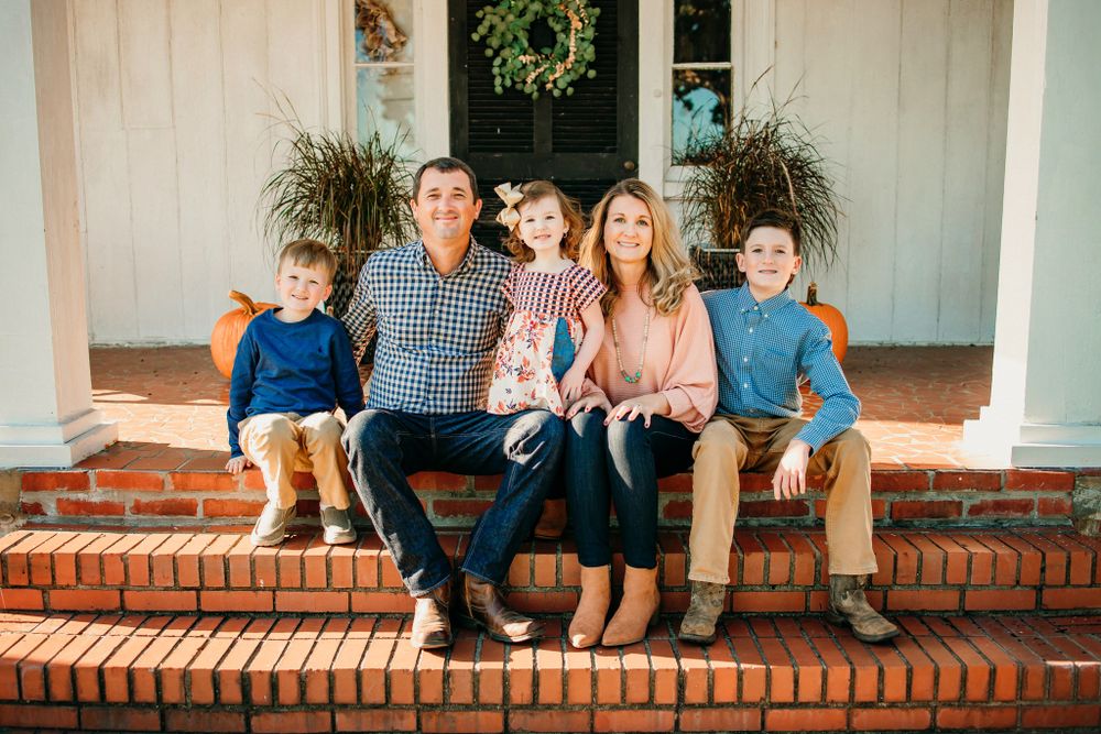 Family sitting together on a brick ledge during a casual outdoor photo session.