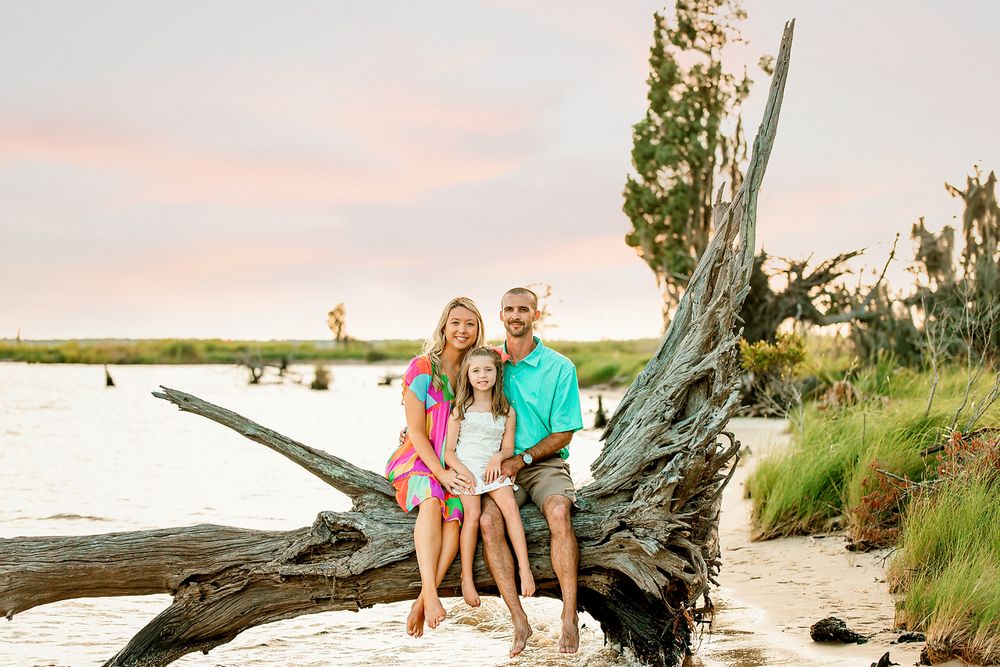 Family relaxing on driftwood at Goose Creek State Park Waterfront.