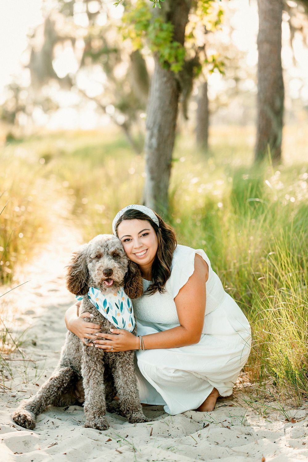 Woman in white dress cuddling with gray poodle dog at Goose Creek State Park Waterfront.