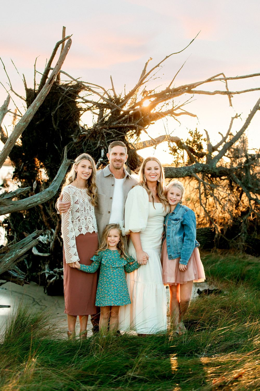 Group photo at sunset with driftwood and ocean backdrop.
