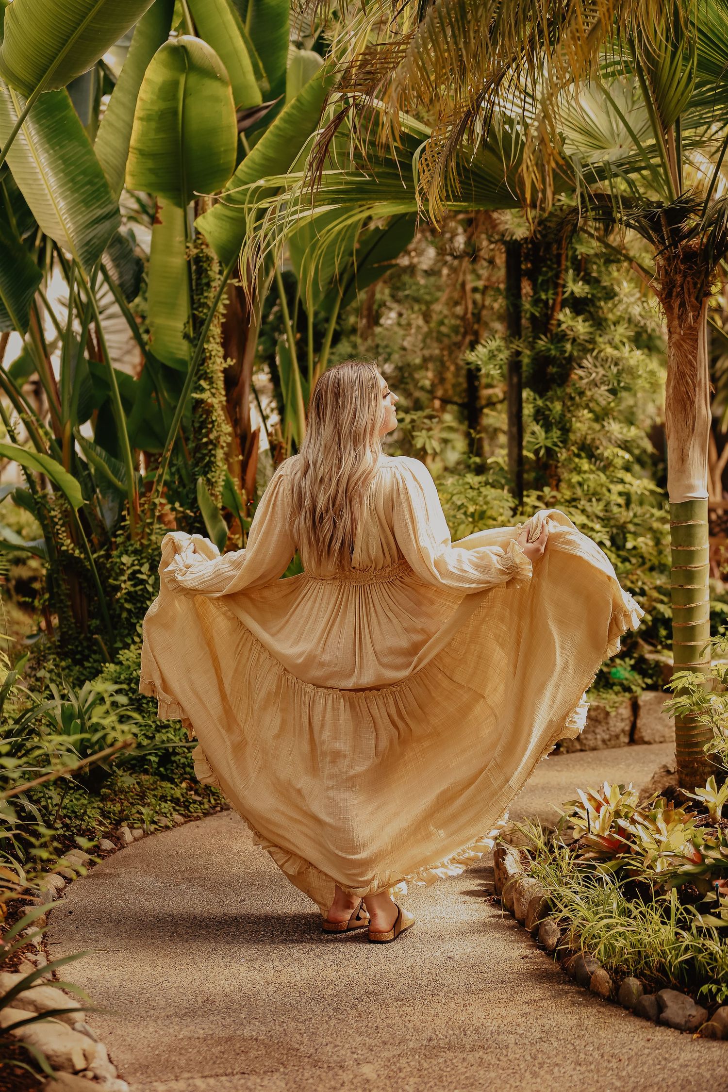 Flowing dress movement captured in garden path surrounded by tropical banana leaves.