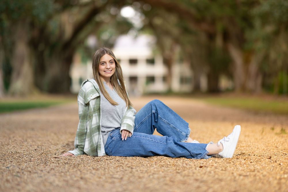 Person in casual outfit relaxing on tree-lined pathway.