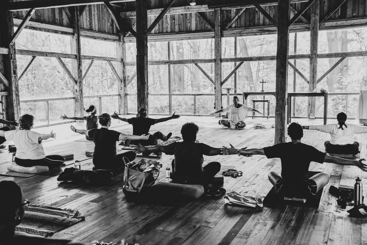 Silhouettes of yoga practitioners stretching on mats in a sunlit studio space.