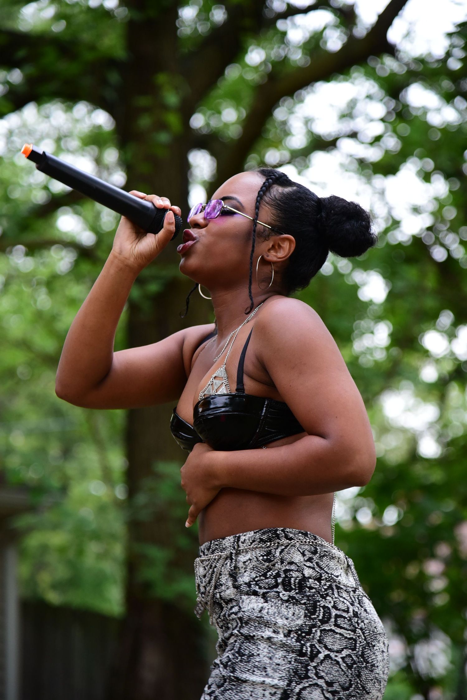Singer performs passionately on stage at an outdoor event wearing a patterned dress.
