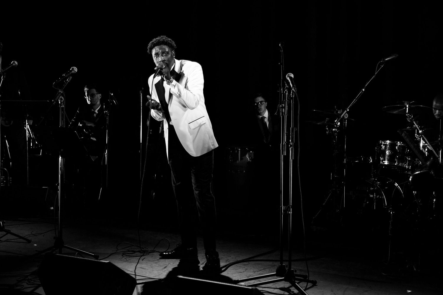 Concert stage performance captured in dramatic black and white lighting.