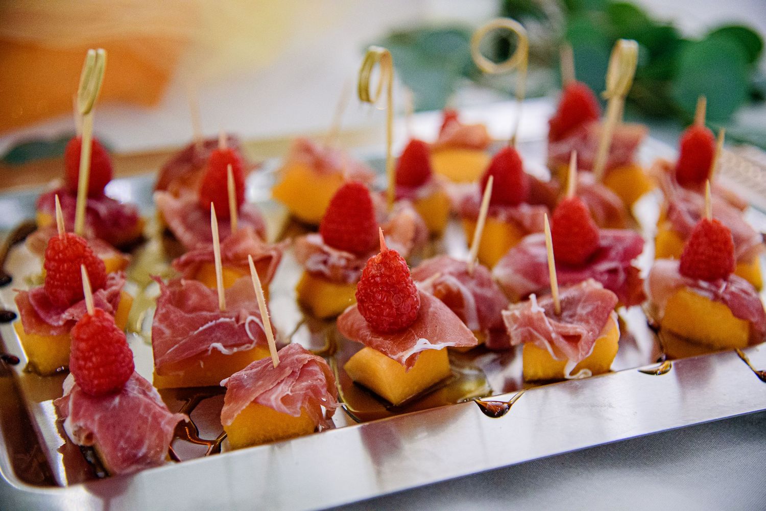 Elegant appetizers with prosciutto and berries arranged on a long serving platter.