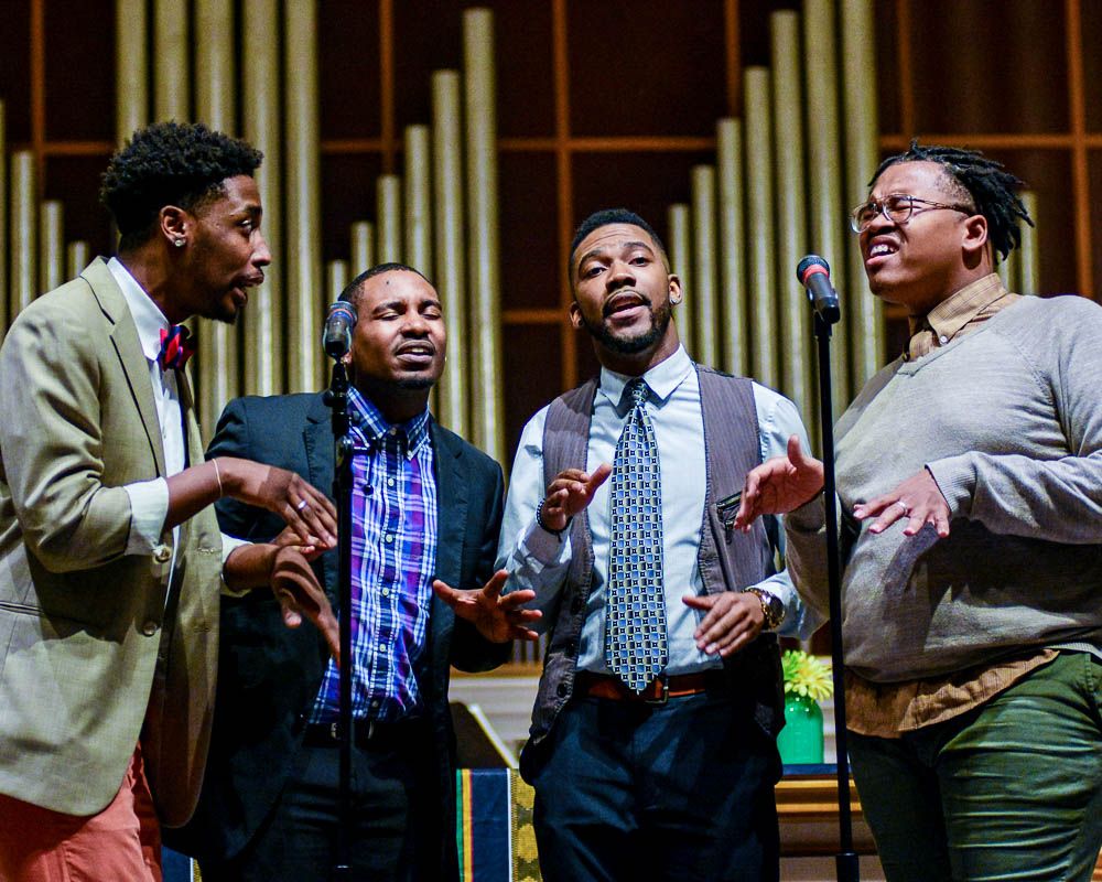 Gospel singers performing with emotion and energy during concert.