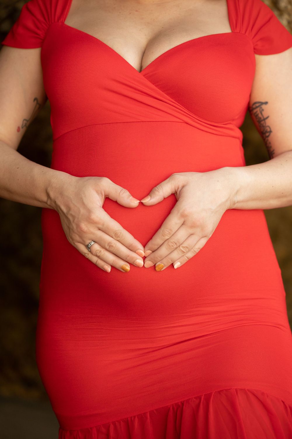 Close-up details of a red maternity dress with ruched bodice and sweetheart neckline.