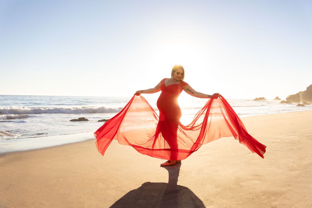 Silhouette of flowing red dress movement captured against sunset beach backdrop.
