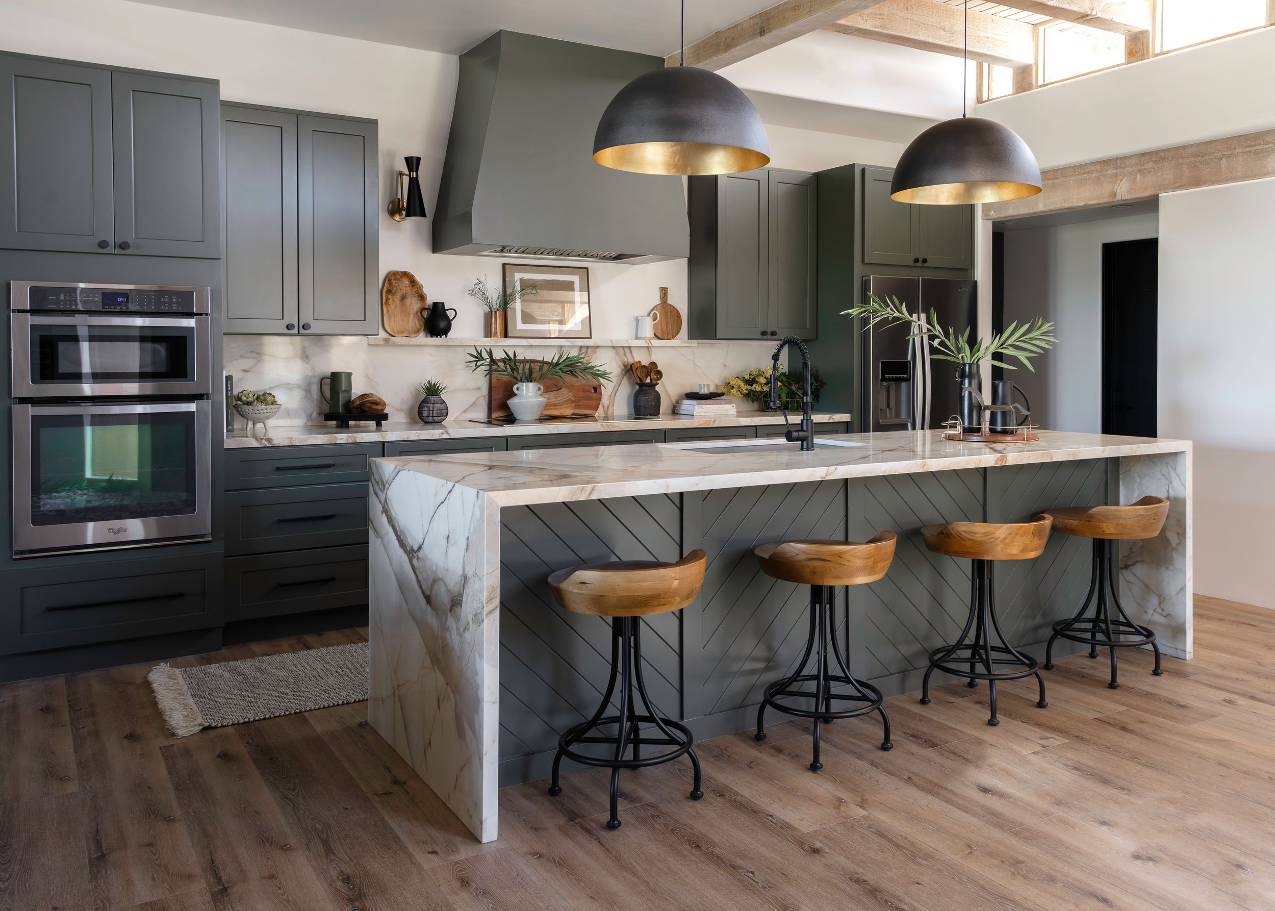 Modern kitchen with dark gray cabinets, marble island, and industrial bar stools.
