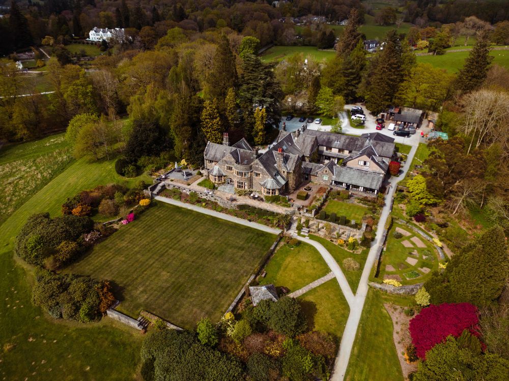 Aerial view of elegant estate venue with manicured gardens and surrounding woodland.