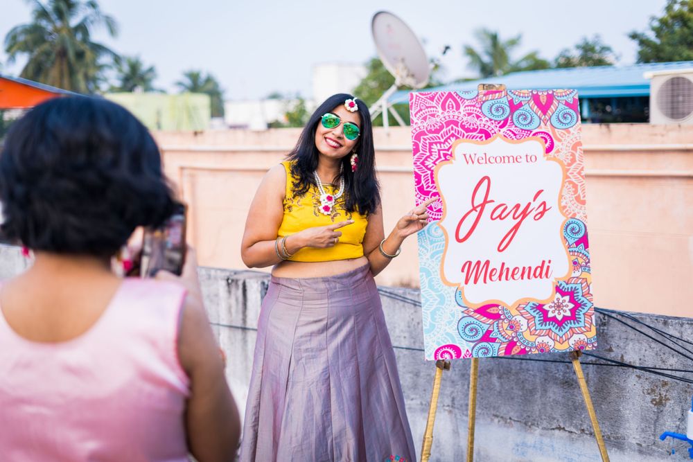 A decorative pink and white welcome sign stands on an easel at an outdoor celebration.