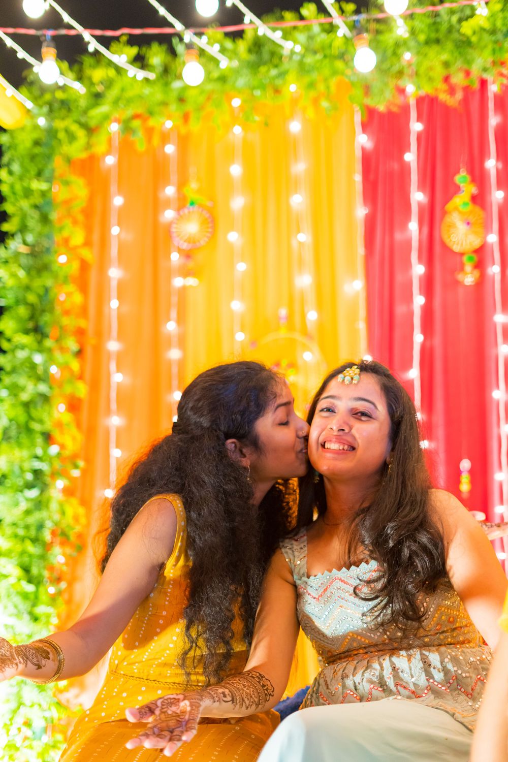 Candid moment during celebration with vibrant yellow and orange decorative backdrop.