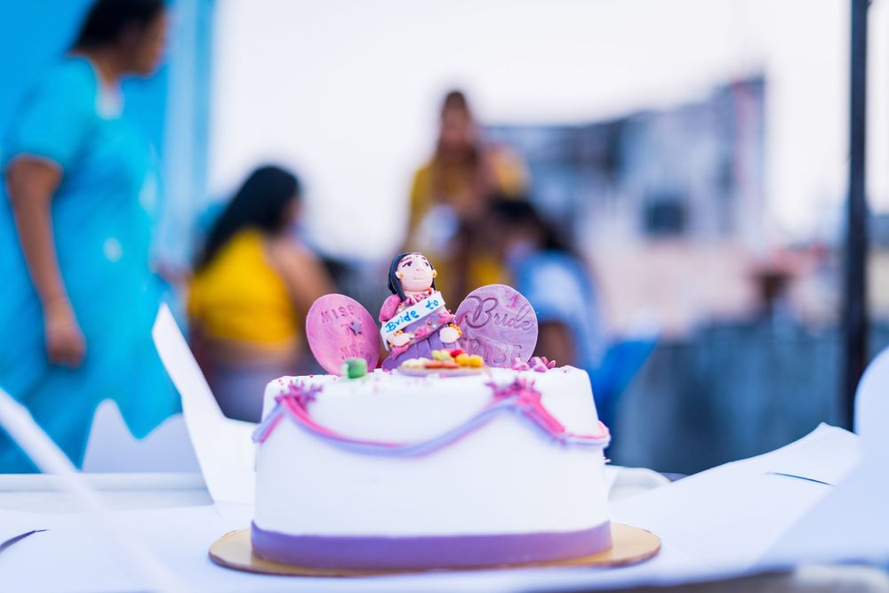 Purple and white decorated cake with Minnie Mouse topper sits on a white table.