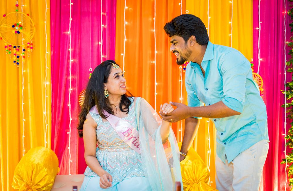 Couple interacting against bright orange and pink draped backdrop during celebration.